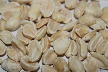 Düz bir yüzeyde kavrulmuş fıstık koleksiyonu duruyor. Mutfak parlak ve düzenli. Fıstıklar farklı boyutlarda ve açık renk gösteriyor..