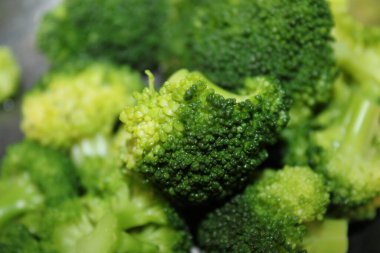 Doğranmış brokoli pişirmeye hazır bir kasede oturur. Mutfağın ışıklandırması iyi. Yeşiller taze ve canlı. Beslenme değerlerini gösteriyor..