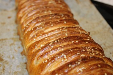 Mutfaktaki tepside duran uzun bir somun hamur işi. Yüzeyi altın kahverengidir ve susam tohumlarıyla kaplıdır. Pişirme işlemi günün erken saatlerinde gerçekleşti..