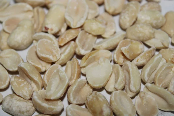 Düz bir yüzeyde kavrulmuş fıstık koleksiyonu duruyor. Mutfak parlak ve düzenli. Fıstıklar farklı boyutlarda ve açık renk gösteriyor..