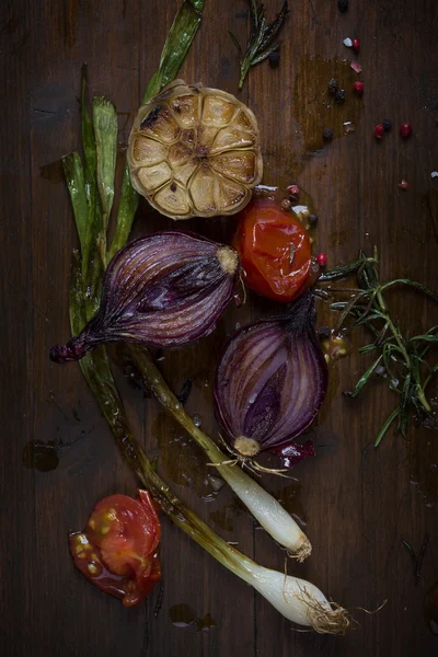 Gegrillte Zwiebeln und Gemüse auf Schneidebrett auf dunklem Holzboden — Stockfoto