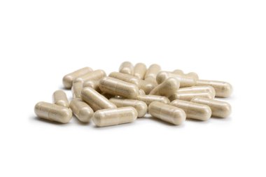 İzole edilmiş beyaz arka planda bej renkli haplar veya kapsüller yığını yakın plan. Seçici Odaklanma.