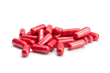 İzole edilmiş beyaz arka planda kırmızı renkli haplar veya kapsüller yığını yakın plan. Seçici Odaklanma.