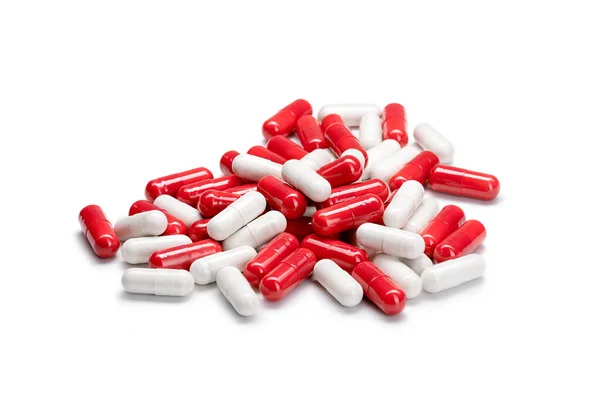 Zbliżenie stos czerwonych i białych kolorowych tabletek lub kapsułek na izolowanym białym tle. Skupienie selektywne. — Zdjęcie stockowe