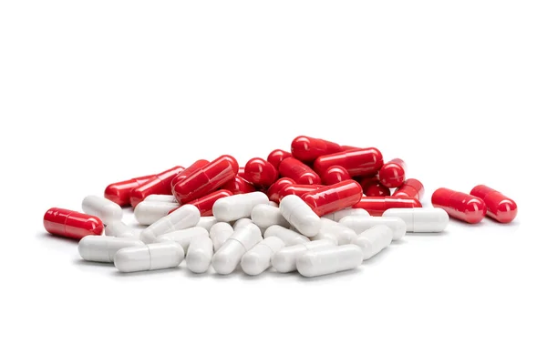 Close-up van een stapel rood-wit gekleurde pillen of capsules op geïsoleerde witte achtergrond. Selectieve focus. — Stockfoto