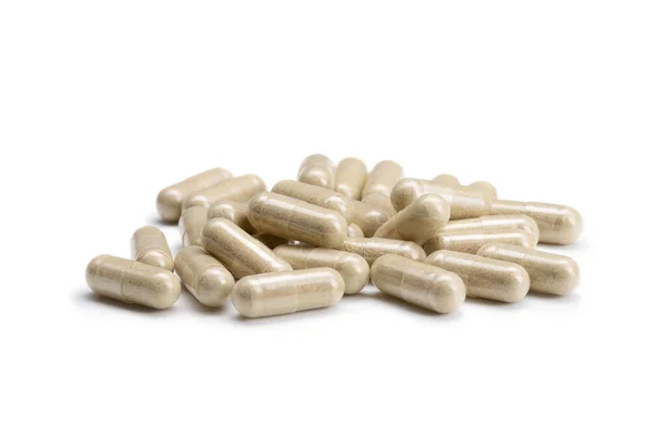 İzole edilmiş beyaz arka planda bej renkli haplar veya kapsüller yığını yakın plan. Seçici Odaklanma.