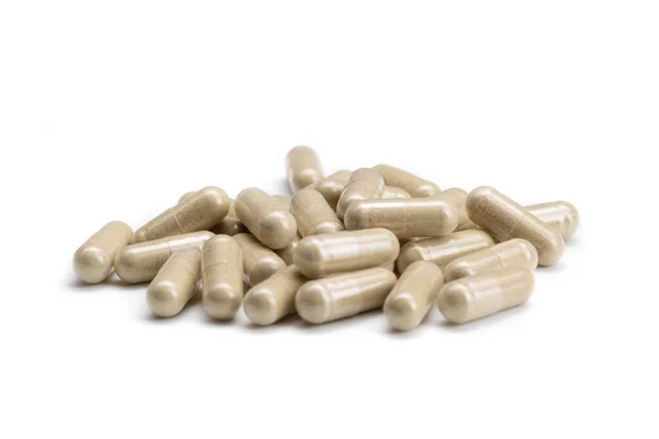 Gros plan d'une pile de pilules ou capsules de couleur beige sur fond blanc isolé. Focus sélectif. — Photo