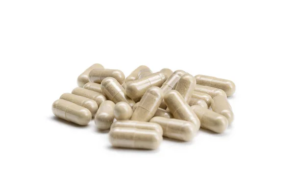 İzole edilmiş beyaz arka planda bej renkli haplar veya kapsüller yığını yakın plan. Seçici Odaklanma.