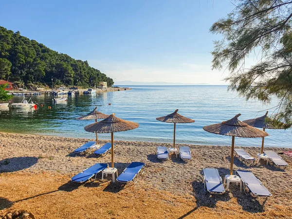 空のサンラウンジャーとビーチの傘とギリシャの島の原始的な湾の景色. — ストック写真
