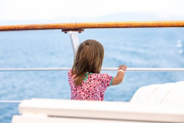 Feribot yolculuğunun tadını çıkaran sevimli genç kız derin mavi denize bakıyor. Yunanistan 'da yaz tatilinde eğlenen bir çocuk. Çocuk tekneye biniyor..
