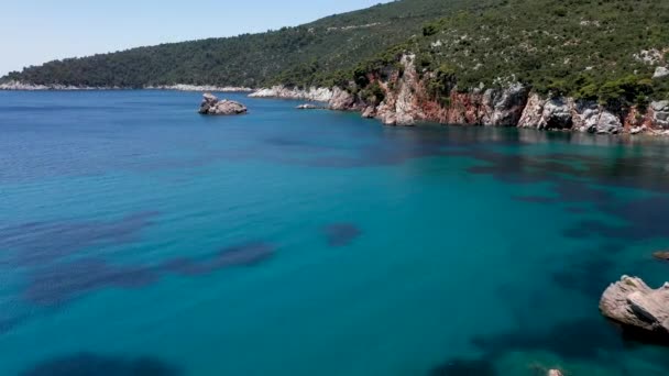 Повітряний дрон дивиться на скелясте узбережжя, кришталево чисті води Егейського моря, туристичні пляжі і багато зелених на острові Скопелос, Греція. Типовий вид на багато подібних грецьких островів. — стокове відео