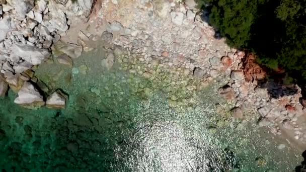 Uitzicht op een drone vanuit de lucht over een rotsachtige kustlijn, kristalhelder zeewater in de Egeïsche Zee, toeristische stranden en veel groen op het eiland Skopelos, Griekenland. Een typisch uitzicht op vele gelijkaardige Griekse eilanden. — Stockvideo