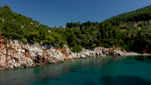 Flygdrönare utsikt över en stenig kust, kristallklart Egeiska havet vatten, turistiska stränder och massor av grönska i Skopelos ön, Grekland. En typisk vy över många liknande grekiska öar. — Stockvideo