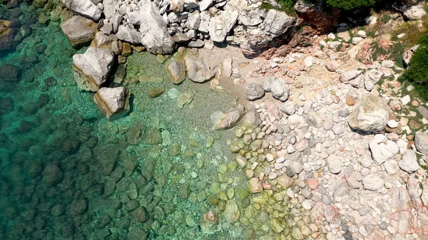 Uitzicht op een drone vanuit de lucht over een rotsachtige kustlijn, kristalhelder zeewater in de Egeïsche Zee, toeristische stranden en veel groen op het eiland Skopelos, Griekenland. Een typisch uitzicht op vele gelijkaardige Griekse eilanden. — Stockfoto