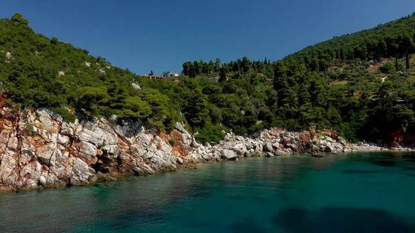 Dron powietrzny z widokiem na skaliste wybrzeże, krystalicznie czyste wody Morza Egejskiego, plaże turystyczne i mnóstwo zieleni na wyspie Skopelos w Grecji. Typowy widok na wiele podobnych greckich wysp. — Zdjęcie stockowe