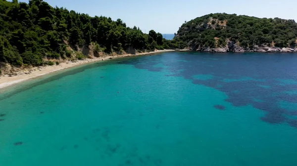 Légi drón kilátás egy sziklás tengerparton, kristálytiszta égei-tengeri vizek, turisztikai strandok és sok zöld Skopelos sziget, Görögország. Jellemző kilátás sok hasonló görög szigetre. — Stock Fotó