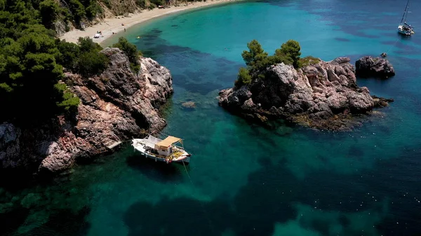 Légi drón kilátás egy sziklás tengerparton, kristálytiszta égei-tengeri vizek, turisztikai strandok és sok zöld Skopelos sziget, Görögország. Jellemző kilátás sok hasonló görög szigetre. — Stock Fotó