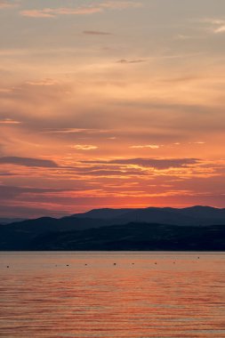 Golden sunset over a serene sea, with gentle waves and clouds illuminated by the warm evening glow in Greece.