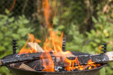 Güneşli bir günde, bir barbekü partisinde yanan ateş..