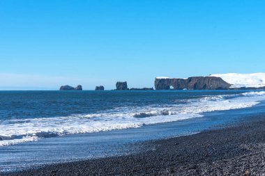 Dyrholaey, İzlanda 'nın kış manzarası. Siyah kumlu, deniz fenerli ve okyanusta volkanik kayalardan oluşan büyük kemerli güzel bir yarımadanın kış manzarası..