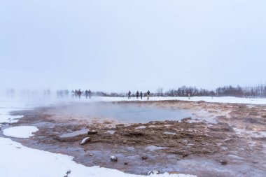 Turistler Strokkur 'un etrafında durup İzlanda' daki patlamayı bekliyorlar. Strokkur 'un patlaması, İzlanda' nın güneybatısındaki Haukadalur jeotermal bölgesinde bulunan bir gayzer çeşmesi. Haukadalur, Altın Çember 'in bir parçası..