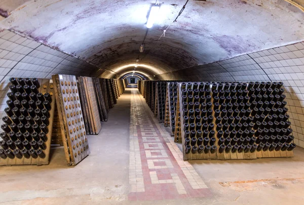 Abrau-Durso, Rusya - 2 Mart 2021: Şampanya ve köpüklü şarap fabrikası Abrau Durso, Rusya. Eski şarap mahzeninde bir yığın şarap şişesi.