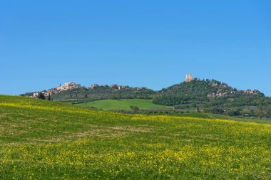 İtalya 'nın Toskana kentindeki selvi ağaçları ve renkli bahar çiçekleriyle ortaçağ küçük kasabasının harika bahar manzarası. Tipik Toskana manzarası.