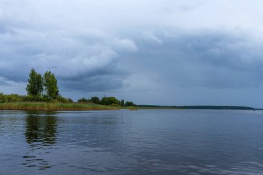 Fırtına öncesi panoramik Seliger Gölü manzarası. Fırtınalı bir gökyüzünün altındaki orman gölü.