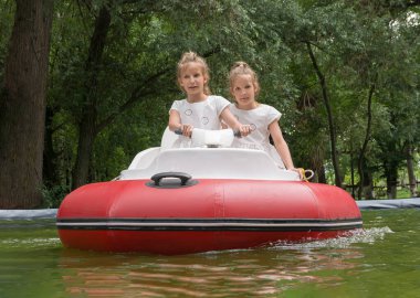 Eğlence parkında kırmızı şişme motorlu tekneye binen genç kızlar