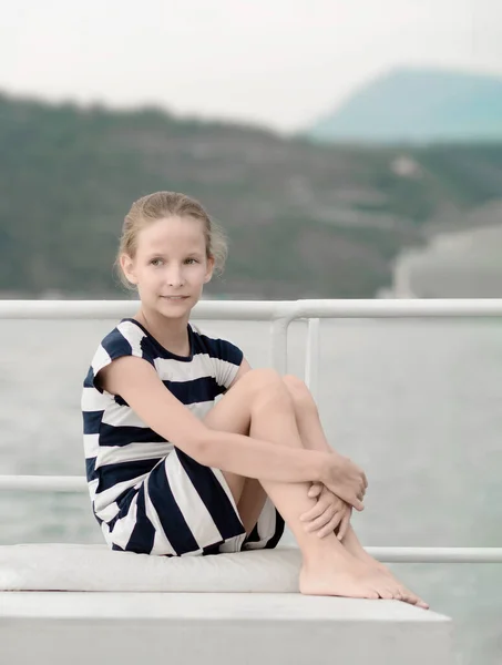 Nastolatka 9 lat siedzi na parapecie nad morzem i górami. Letni wieczór — Zdjęcie stockowe