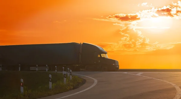 Caminhão vai na estrada ao pôr do sol — Fotografia de Stock