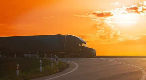грузовик едет по шоссе на закате
