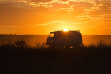 Minivan gün batımında bir köy yolunda gidiyor.
