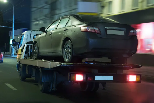 transportation of the car on the tow truck in the city at night. Blurred motion