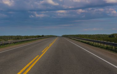 Mavi gökyüzünün altında bulutlu boş bir banliyö otoyolu