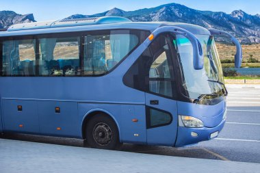 Dağ manzarasının önündeki durakta gölü olan bir turist otobüsü.