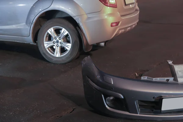 Accident on the road at night. A broken, torn bumper lies on the road.