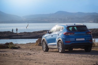 Deniz kenarındaki off-road aracı bir dağ manzarasının arka planına karşı.