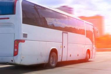 Beyaz turist otobüsü şehir caddesinde gidiyor.