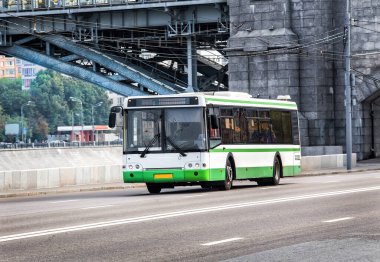 Beyaz şehir otobüsü cadde boyunca gidiyor.