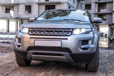 Modern bir SUV yapım aşamasındaki bir binanın önünde. Yakın plan.