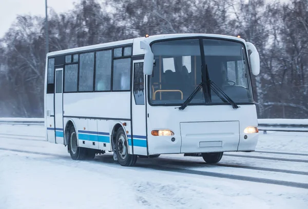 bus moves in winter along a snowy road.