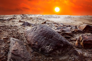 Taş çölün üzerinde kızıl gün batımı. Manzara