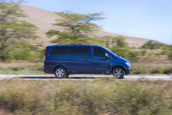 Minibus tepe arkaplanına doğru gidiyor. Bulanık arkaplan.