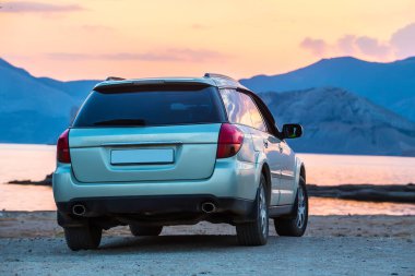 Araba deniz kıyısında, plajda, akşamleyin, gün batımında.