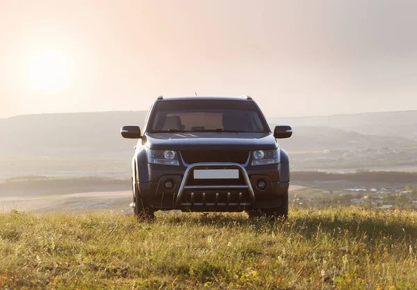 山の背景に夜明けのフィールド上のSuv — ストック写真