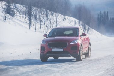 SUV kışın dağlardaki bir kır yolunda hareket eder.