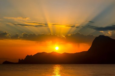 Deniz kıyısındaki dağların üzerinde güzel bir günbatımı