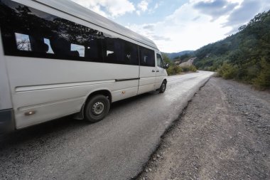Minibüs dağlardaki virajlı yolda ilerliyor.
