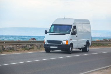 Minibüs deniz kıyısında yol boyunca ilerliyor.
